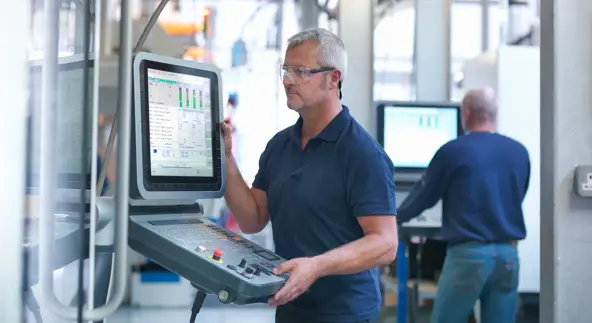 engineers at lathe controls in factory